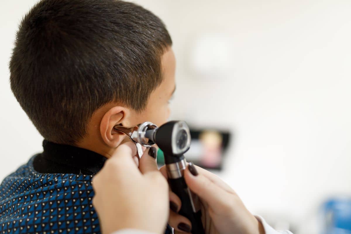 Doctor using a medical device to inspect the inner ear of a child patient