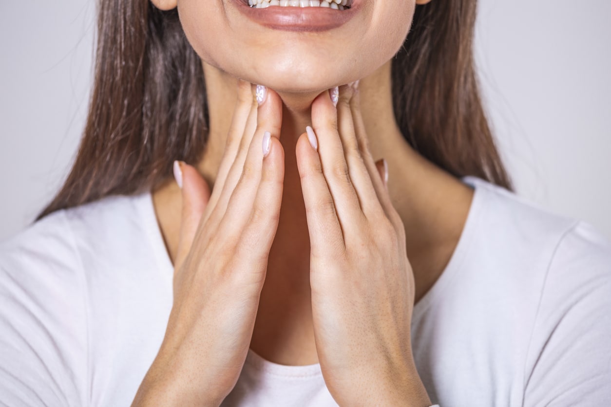 Woman holds hands to throat