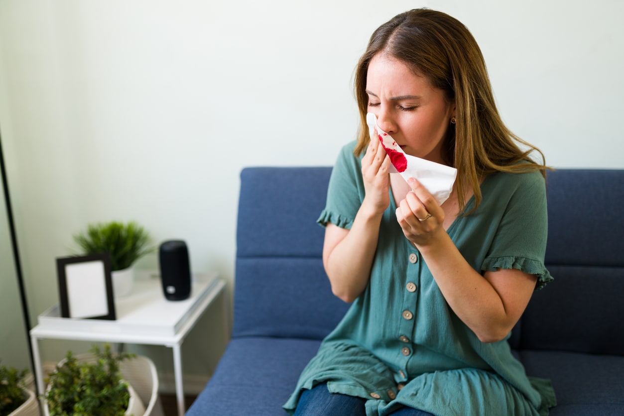 Woman leaning forward with a nosebleed