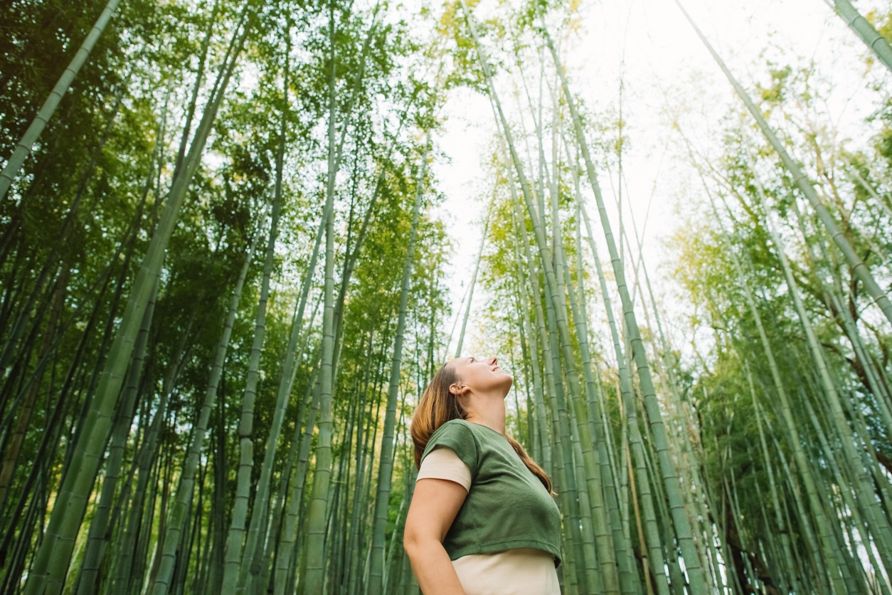 Woman standing in a bamboo forest enjoying earth day