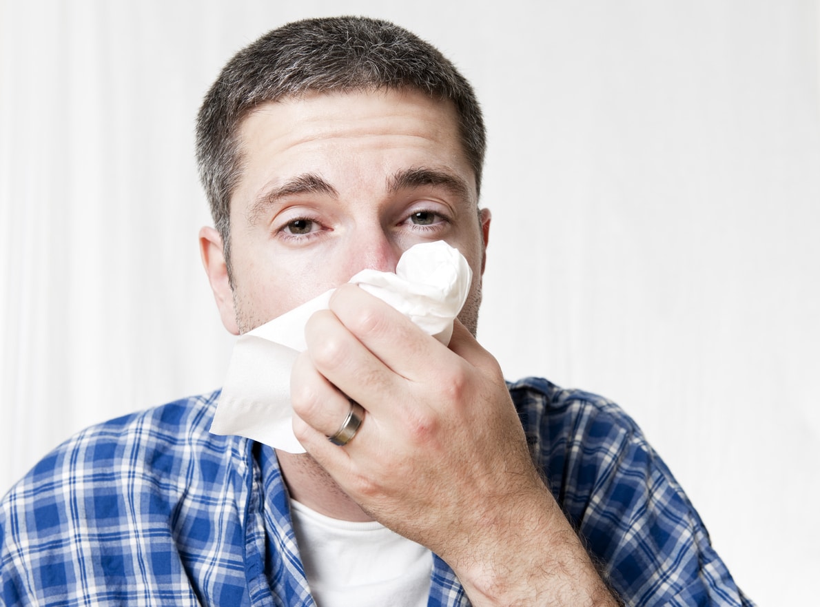 Man blowing his nose into a tissue.