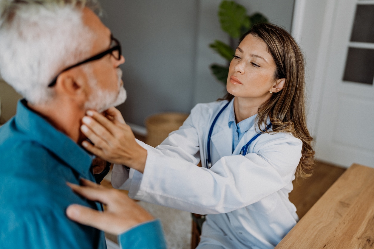 ENT provider feeling a patient's throat.