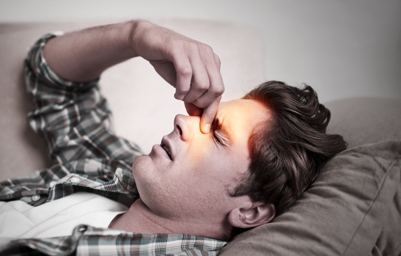 Man with nose pain pinches nose