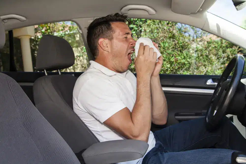 Man with allergies sneezes in his car